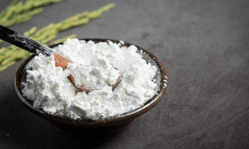white rice flour on small bowl with rice plant